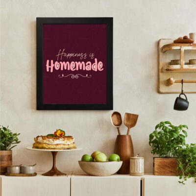 Happiness is Homemade kitchen wall art with playful pink and white fonts on a maroon background, featuring decorative swirls. There is a vegetable table, and above it, there is wall art.