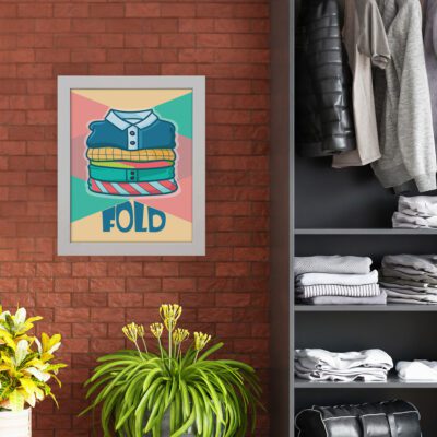 Illustration of folded clothes with "FOLD" text on a pink and teal background, abstract shapes, and vibrant modern laundry room wall art. hung on the wall nearby cupboard