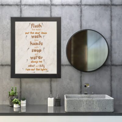 Bathroom wall art with a cream marble background and warm brown text saying "Flush the toilet, put the seat down, wash your hands." hung on the wall in the bathroom a black frame