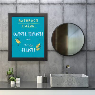 Bathroom wall art with teal blue background, white text saying "BATHROOM rules WASH, BRUSH and always FLUSH," and yellow decorative leaves. hung on the wall in the bathroom a black frame