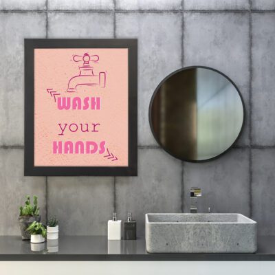 Wash your HANDS bathroom wall art with bold pink text and a red water tap on a pink background, adding a fun, retro vibe to your bathroom. hung on the wall in the bathroom a black frame