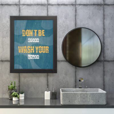 Don't Be Gross Wash Your Hands bathroom wall art with bold yellow and white text on a dark blue textured background. hung on the wall in the bathroom, a black frame