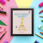 Infidu wall art featuring a cute giraffe with Psalm 91:11 'God's Angels Protect Me All The Time' in the blue and orange text displayed on the wall in a black frame in a colorful background