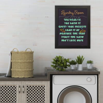 Laundry wall art with bold light blue, yellow, and white text on a navy blue background, featuring a hanger design and funny laundry quotes. hung on the wall the laundry wall art under the washing machine