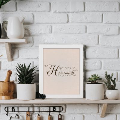 Happiness Is Homemade kitchen wall art with soft brown cursive text on a beige textured background, perfect for modern kitchen wall decor. displayed on the table