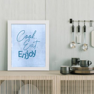 Cook. Eat. Enjoy. kitchen wall art with light blue text on a textured background, adding a modern touch to your kitchen decor. displayed on the table in a white frame