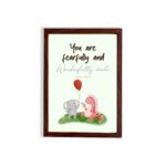 Cute wall art featuring an elephant and dinosaur with the verse You Are Fearfully and Wonderfully Made from Psalm 139:14. hung on the wall in a brown frame