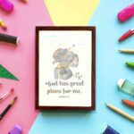 Wall art featuring a grey elephant with a party hat and a yellow gift, displaying the text God Has Great Plans For Me. displayed on the wall in a brown frame in a colorful background