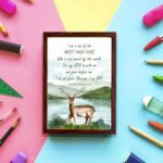 The lakeside scene with a deer and mountains features the verse I Am A Son Of The Most High King in calming colors. displayed on the wall in a brown frame in a colorful background