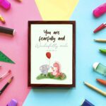 Cute wall art featuring an elephant and dinosaur with the verse You Are Fearfully and Wonderfully Made from Psalm 139:14. displayed on the wall in a brown frame in colorful background