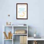 You Are a Child of God wall art featuring a white elephant on a crescent moon with stars and pastel flags. displayed on the wall in a brown frame