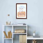 A cute white bear holding a wooden sign with the verse We Love Because He First Loved Us - 1 John 4:19 against a blue sky with clouds. displayed on the wall in a brown frame