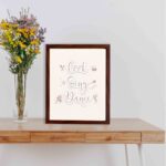 Cook Sing Dance kitchen wall art with pastel pink tones, a beige background, and musical notes.