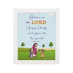 Wall art with a green field, trees, and cartoon figures of Jesus and children, featuring the text 'Believe in the Lord Jesus Christ and you will be saved. hung on the wall in a white frame