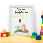 Cute wall art featuring an elephant and dinosaur with the verse You Are Fearfully and Wonderfully Made from Psalm 139:14. displayed on the table in a white frame