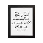 The Lord Remembers Us And Will Bless Us - Psalm 115:12 Bible Verse Wall Art on a white background with black text. hung on the wall in a black frame