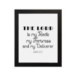 Bible wall art featuring Psalm 18:2 "The Lord Is My Rock, My Fortress, And My Deliverer" in black text on a white background. hung on the wall in a black frame