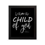 Black wall art with white text reading 'I am a CHILD of god' from John 1:12, showcasing a mix of cursive and bold lettering. hung on the wall in a black frame