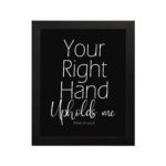 Christian wall art with the text Your Right Hand Upholds Me and PSALM 63:8 on a black background. hung on the wall in a black frame