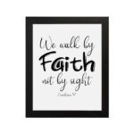 Christian wall art featuring the quote We walk by faith not by sight from Corinthians 5:7 in black text on a white background. hung on the wall in a black frame