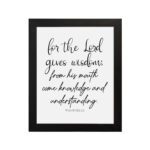 Proverbs 2:6 Christian wall art with black cursive text on a white background. For the Lord gives wisdom. hung on the wall in a black frame