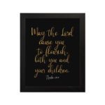 May The Lord Cause You To Flourish Both You And Your Children - Psalm 115:14 Christian Wall Art in golden text on black background. hung on the wall in a black frame