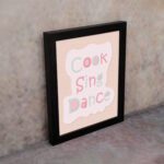 Cook Sing Dance Kitchen Wall Art with pastel pink, green, and blue text on a peach background, perfect for cheerful kitchen decor.