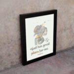 Wall art featuring a grey elephant with a party hat and a yellow gift, displaying the text God Has Great Plans For Me. displayed on the wall in a black frame