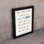 Colorful wall art featuring Jeremiah 29:11, For I Know The Plans I Have For You, with rainbow text on a white background. displayed on the wall in a black frame