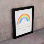 Cheerful rainbow wall art with the text Rainbows Are Your Promises in colorful letters, designed for kids' room decor. displayed on the wall in a black frame