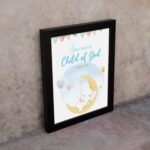 You Are a Child of God wall art featuring a white elephant on a crescent moon with stars and pastel flags. displayed on the wall in a black frame