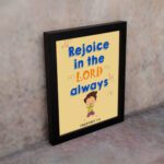 Rejoice in the Lord always, Philippians 4:4 Christian wall art with smiling child and bright colors. displayed on the wall in a black frame