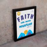 Wall art with the text Faith can move mountains from Matthew 17:20, featuring a sun rising over mountains. displayed on the wall in a black frame