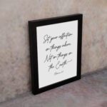 Set Your Affection on Things Above Colossians 3:2 Bible Verse Wall Art on a white background with black text and leaf decorations. displayed on the wall in a black frame