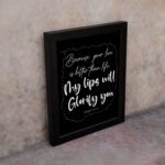 Wall art featuring Psalm 63:3 - 'Because Your Love Is Better Than Life, My Lips Will Glorify You' in white on a black background. displayed on the wall in a black frame