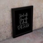 Christian wall art with the phrases Start With Jesus, Stay With Jesus, and End With Jesus in white text on a black background. displayed on the wall in a black frame