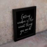 Christian wall art with the quote 'Getting wisdom is the wisest thing you can do' from Proverbs 4:7 in white text on a black background. displayed on the wall in a black frame