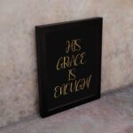 His Grace Is Enough Christian wall art in gold text on a black background, perfect for home decor and inspirational reminders. displayed on the wall in a black frame