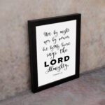 Not By Might Nor By Power Zechariah 4:6 Christian wall art with black text on a white background. displayed on the wall in a black frame