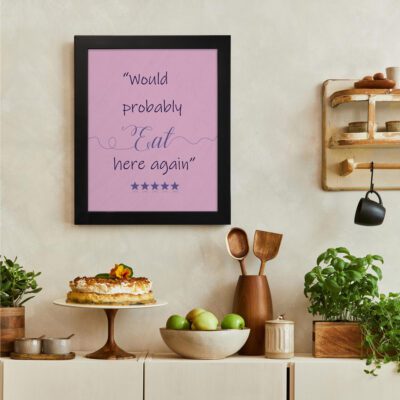 Would Probably Eat Here Again kitchen wall art with a light pink background, cursive and bold text, blue accents, and five blue stars. There is a vegetable table, and above it, there is wall art.