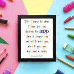 Colorful wall art featuring Jeremiah 29:11, For I Know The Plans I Have For You, with rainbow text on a white background. displayed on the wall in a black frame in a colorful background