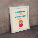 Cute teddy bear holding a heart with Trust in the Lord with all your heart text above, Proverbs 3:5 wall art design. displayed on the wall in a white frame