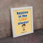 Rejoice in the Lord always, Philippians 4:4 Christian wall art with smiling child and bright colors. displayed on the wall in a white frame