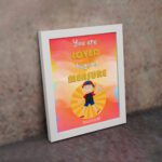 Colorful wall art featuring a happy child holding a heart with the quote You Are Loved Beyond Measure and Romans 8:38. displayed on the wall in a white frame