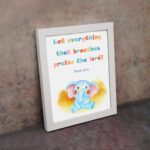 Colorful elephant wall art with the verse "Let everything that breathes praise the Lord!" for kids' room decor. displayed on the wall in a white frame