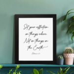 Set Your Affection on Things Above Colossians 3:2 Bible Verse Wall Art on a white background with black text and leaf decorations. displayed on the table in a black frame