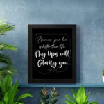 Wall art featuring Psalm 63:3 - 'Because Your Love Is Better Than Life, My Lips Will Glorify You' in white on a black background. displayed on the wall in a black frame