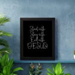 Christian wall art with the phrases Start With Jesus, Stay With Jesus, and End With Jesus in white text on a black background. displayed on the wall in a black frame