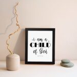 I Am A Child of God John 1:12 Christian Wall Art with black text on a white background displayed on the wall in a black frame