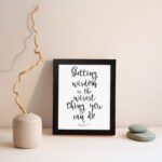 Wall art featuring the quote 'Getting wisdom is the wisest thing you can do' from Proverbs 4:7 on a white background. displayed on the wall in a black frame